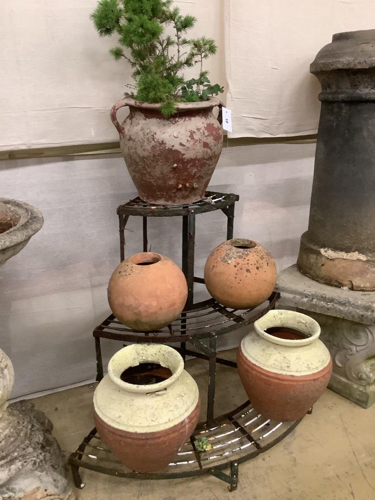 Five assorted terracotta pots together with a wrought iron corner pot stand, height 75cm